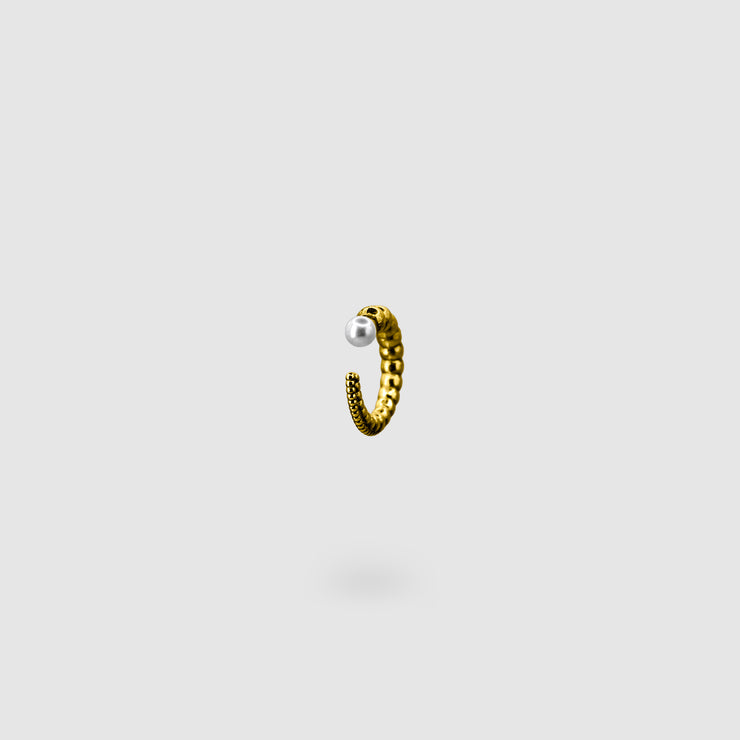 This sculptural ear cuff from the PHAOS collection reimagines the ancient granulation technique through digital design and contemporary craftsmanship. Designed to sit securely without a piercing, its fluid form curves around the ear and finishes with a luminous white glass pearl - adding a touch of shimmer to any look. Available in your choice of gold-plated brass or .925 silver.