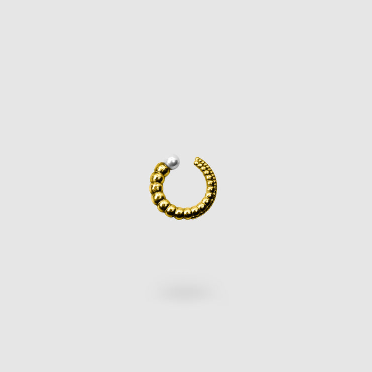 This sculptural ear cuff from the PHAOS collection reimagines the ancient granulation technique through digital design and contemporary craftsmanship. Designed to sit securely without a piercing, its fluid form curves around the ear and finishes with a luminous white glass pearl - adding a touch of shimmer to any look. Available in your choice of gold-plated brass or .925 silver.