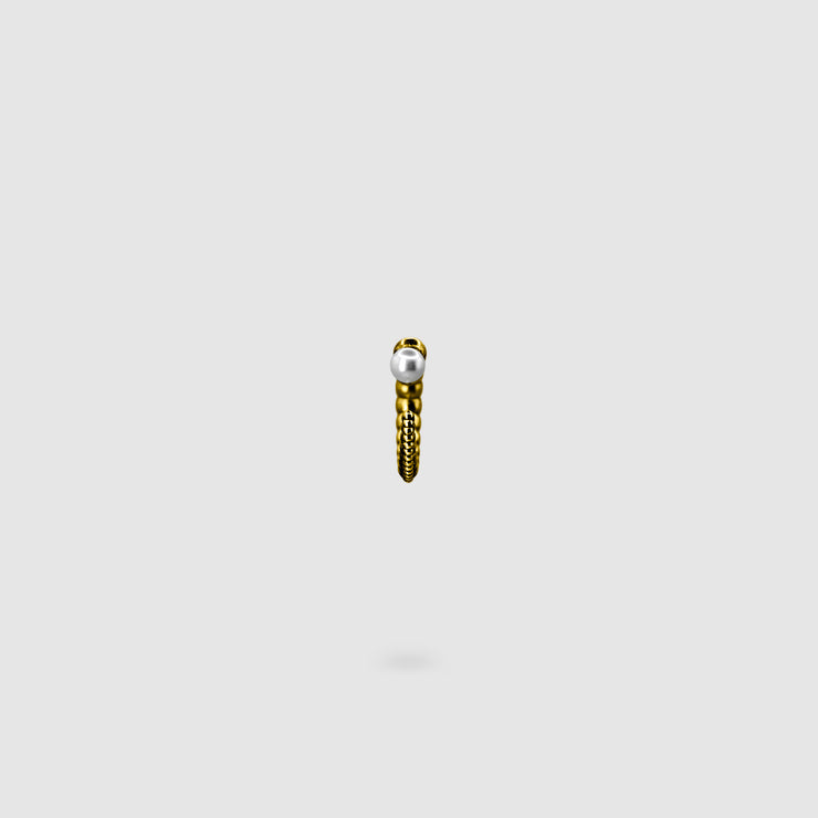 This sculptural ear cuff from the PHAOS collection reimagines the ancient granulation technique through digital design and contemporary craftsmanship. Designed to sit securely without a piercing, its fluid form curves around the ear and finishes with a luminous white glass pearl - adding a touch of shimmer to any look. Available in your choice of gold-plated brass or .925 silver.