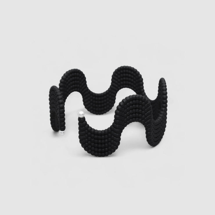 This lightweight cuff bracelet from the PHAOS collection is crafted from hand-dyed, 3D printed bioplastic and accented with glass pearls. Made from a renewable, plant-based polyamide derived from vegetable oil, each piece is hand-finished in your choice of colour; blending sustainable innovation with bold, contemporary design.