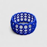 Playful bangle bracelet from 3D printed bioplastic of the PHAOS collection, hand-dyed in royal blue or a pink and red hue. This material is a polyamide powder made out of renewable resources that come from vegetable oil.