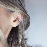 This finely detailed ear cuff from the PHAOS collection offers an innovative reinterpretation of the ancient granulation technique, brought to life through digital design and modern craftsmanship. Its sculptural form wraps elegantly around the ear without the need for a piercing, creating a bold yet refined statement. Available in your choice of gold-plated brass or .925 silver, it’s a contemporary piece that merges heritage with high-tech precision.