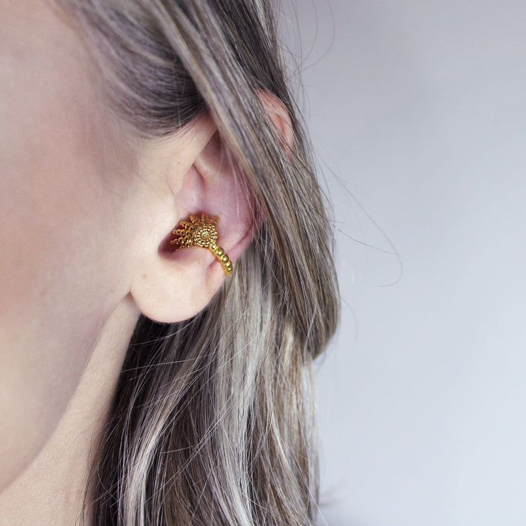This finely detailed ear cuff from the PHAOS collection offers an innovative reinterpretation of the ancient granulation technique, brought to life through digital design and modern craftsmanship. Its sculptural form wraps elegantly around the ear without the need for a piercing, creating a bold yet refined statement. Available in your choice of gold-plated brass or .925 silver, it’s a contemporary piece that merges heritage with high-tech precision.