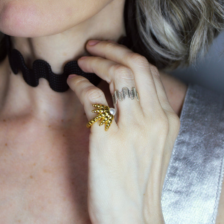 This open ring reimagines the ancient granulation technique with a fresh, contemporary edge, uniting heritage craftsmanship with modern design. Crafted in gold-plated brass or .925 silver as part of the PHAOS collection, it features an artful balance of form and texture, finished with a luminous glass bead for a distinctive statement.