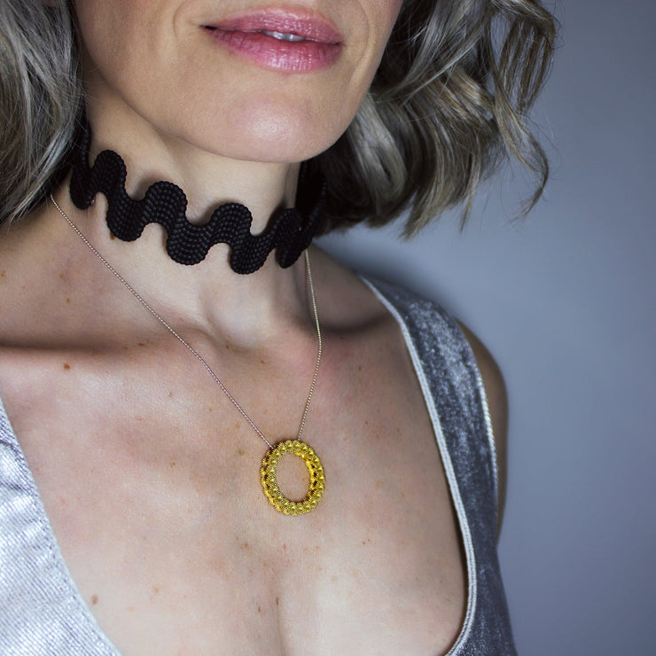Striking yet refined, this pendant features an artfully detailed, geometric design crafted from gold-plated brass and suspended from a .925 silver chain - part of the PHAOS collection. Whether worn alone or layered with other pieces, it adds a subtle edge to any look. 