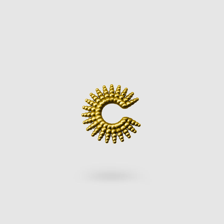 This sophisticated ear cuff from the PHAOS collection reimagines the ancient granulation technique through digital design and contemporary craftsmanship. Designed to sit securely without a piercing, its geometric shape curves around the ear. Available in your choice of gold-plated brass or .925 silver.